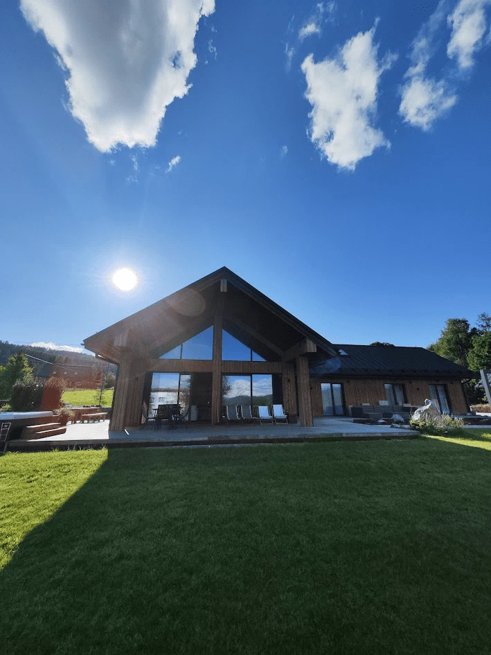 Nowoczesny drewniany dom z dużym tarasem i ogrodem w słoneczny dzień – noclegi Istebna.