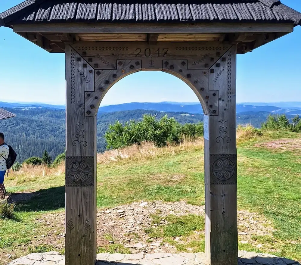 Drewniana brama widokowa na Ochodzitej z panoramą gór w tle.